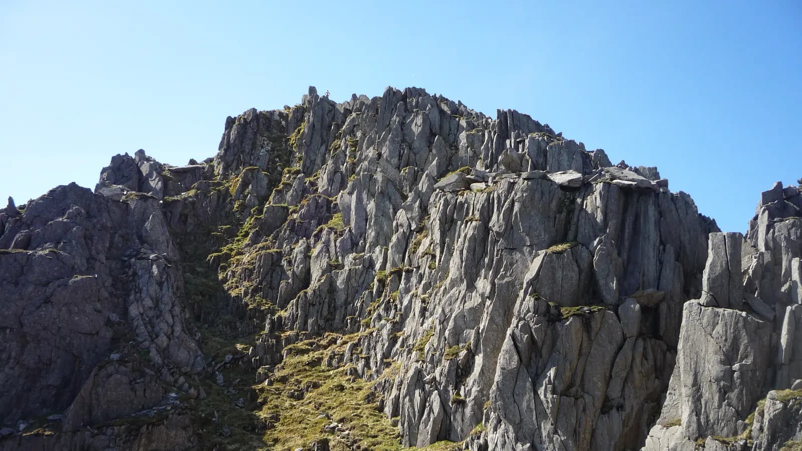 A buttress of broken volcanic rock on Tryfan, fracturing into blocks and ledges at the scale a person could use, with a steep grass-and-scree gully cutting up beside it.